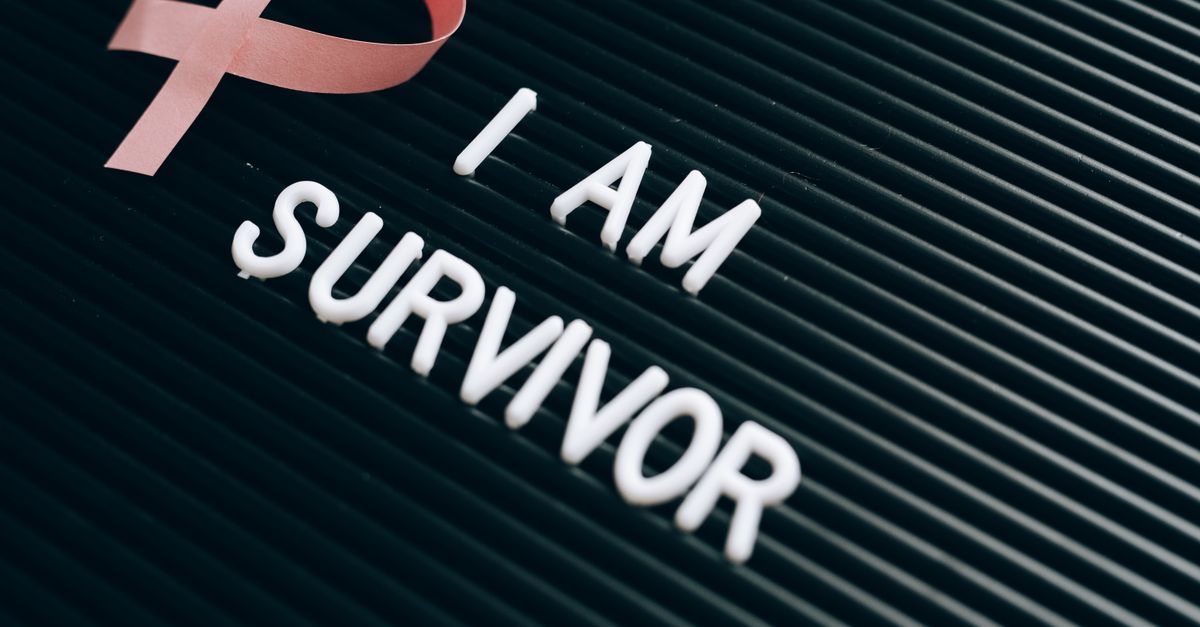 Breast cancer survivor message with pink ribbon and empowering text on board.